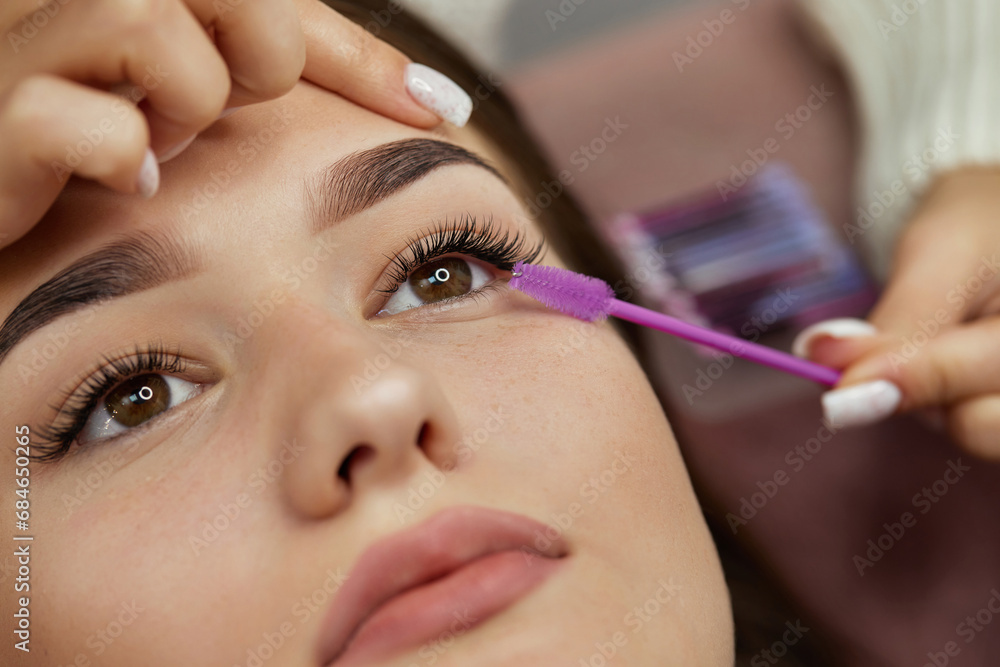 master combs the eyelashes of the client after the eyelash extension procedure. close-up. Cosmetology and skin care master combs the eyelashes of the client after the eyelash extension procedure. close-up. Cosmetology and skin care