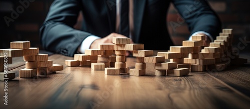 Business crisis manager maintaining stability in a visual representation with wooden dominos copy space image