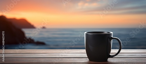 Blurred sunset sea view with black coffee cup Small espresso mug on wooden background copy space image