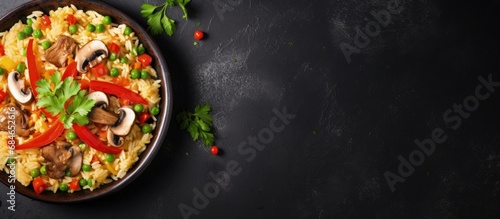 Chicken mushroom paella with vegetables and spices on black bowl top view on concrete table copy space image