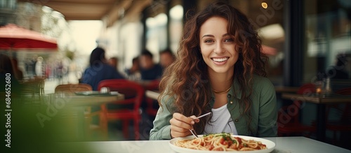Fototapeta Naklejka Na Ścianę i Meble -  Brunette girl enjoying Italian pasta at a street cafe Advertisements design copy space image