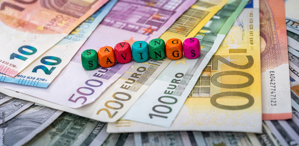 savings word In wooden cubes with euros and dollar bills. savings word In wooden cubes with euros and dollar bills.