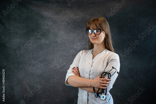 Portrait of female general practitioner or doctor with stethoscope isolated on dark