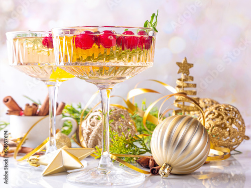 Christmas champagne fruit punch with cranberry, orange, spices and rosemary. Sweet alcohol cocktail glasses, on Christmas and New Year decorated background