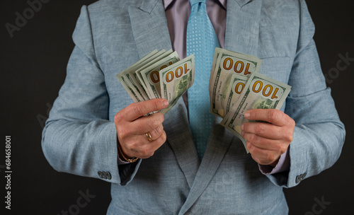 businessman wear suit showing us dollar money banknotes isolated on black
