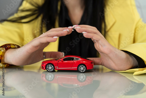  Protection of car  close up  female hands above small red toy car