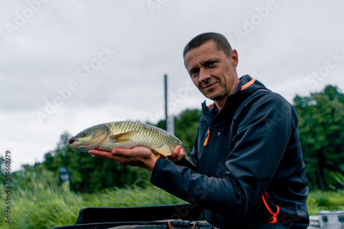 portrait of a professional fisherman holding a carp fish on the bank of a river fishing in reservoirs a good catch