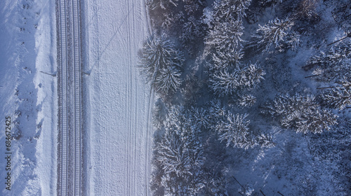 Top view of train track rails crossing through snowy forest in winter near Munich