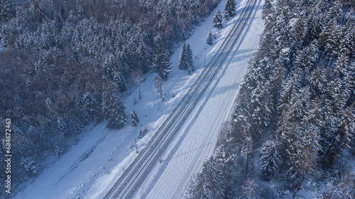 Top view of train track rails crossing through snowy forest in winter near Munich