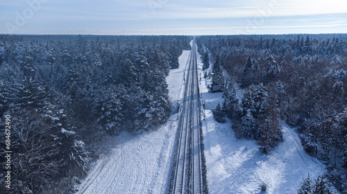 Top view of train track rails crossing through snowy forest in winter near Munich
