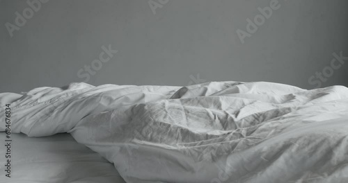 Closeup on unmade bed with cotton bedsheet and soft blanket in bedroom. Crumpled bedding linen in hotel room. Comfort sleeping. Lazy morning photo