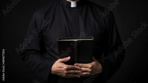 Catholic priest in black robe holds Holy Bible standing in old rural church closeup photo
