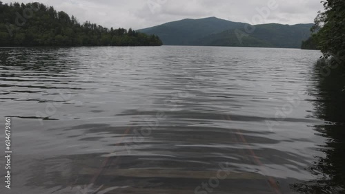 Submerged rail tracks underwater in calm lake in forested mountains photo