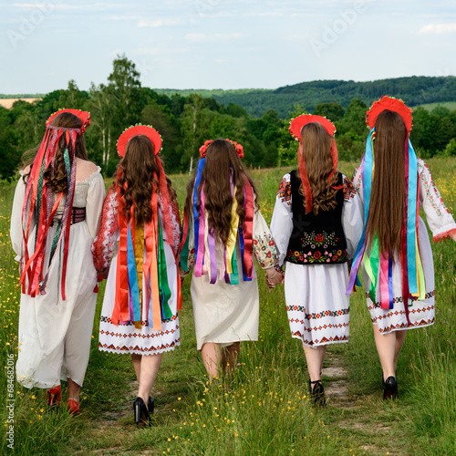 A group of girls are walking in a field, they are dressed in Ukrainian ethnic and national clothes.
