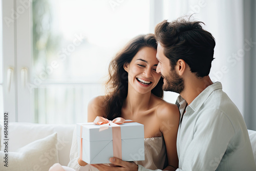 A couple sharing a surprise gift, expressing joy and love in a happy, celebratory moment at home.