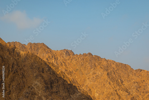 Fujairah mountains, extension of Omani Al Hajar mountain range. Cloudy winter day on empty street.