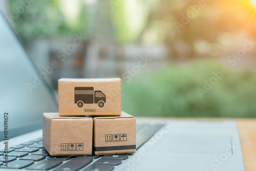 Paper cartons or parcel with shopping cart logo on laptop keyboard for online shopping or ecommerce and delivery service concept. Shopping service online and offer home delivery via the internet. photo