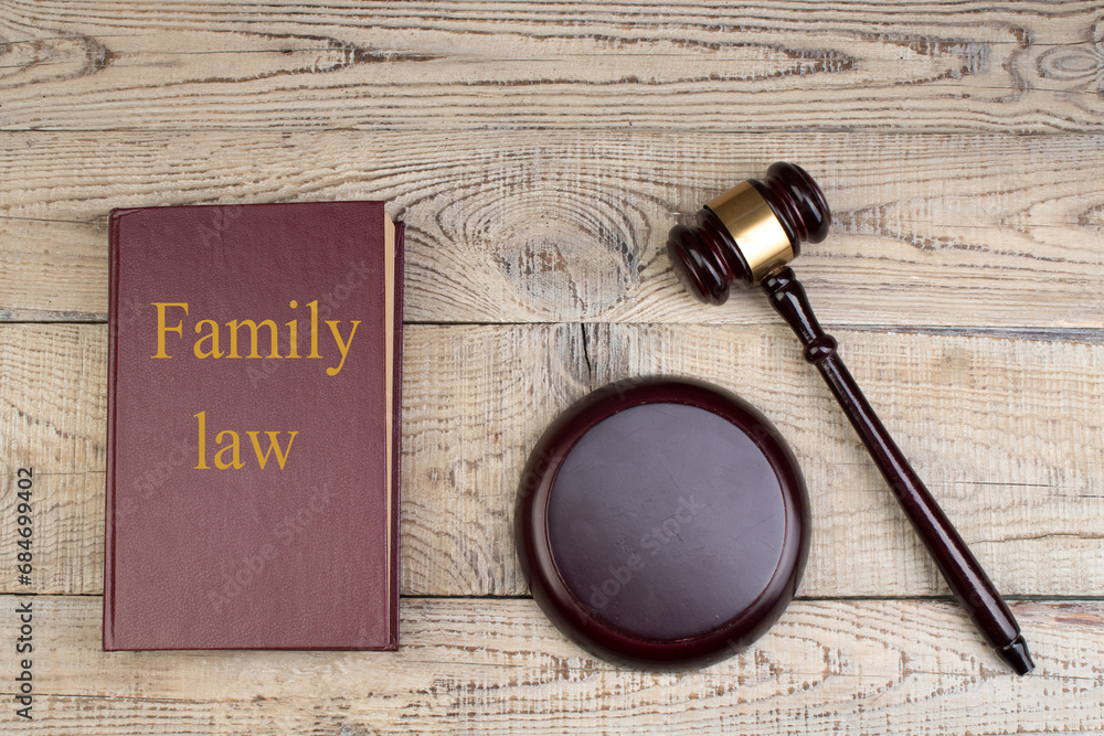 Law concept - Family law. Open law book with a wooden judges gavel on table in a courtroom or law enforcement office on the wooden background. Copy space for text.