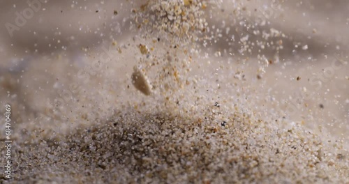 Particles of dry sand are pouring down forming hill at 1000 fps. Close up shot of crumbling natural sand grains, sandy dune. Heap of petrified natural mineral. photo
