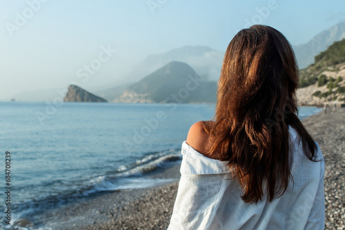 beautiful young woman on vacation, a woman stands with her back to the sea