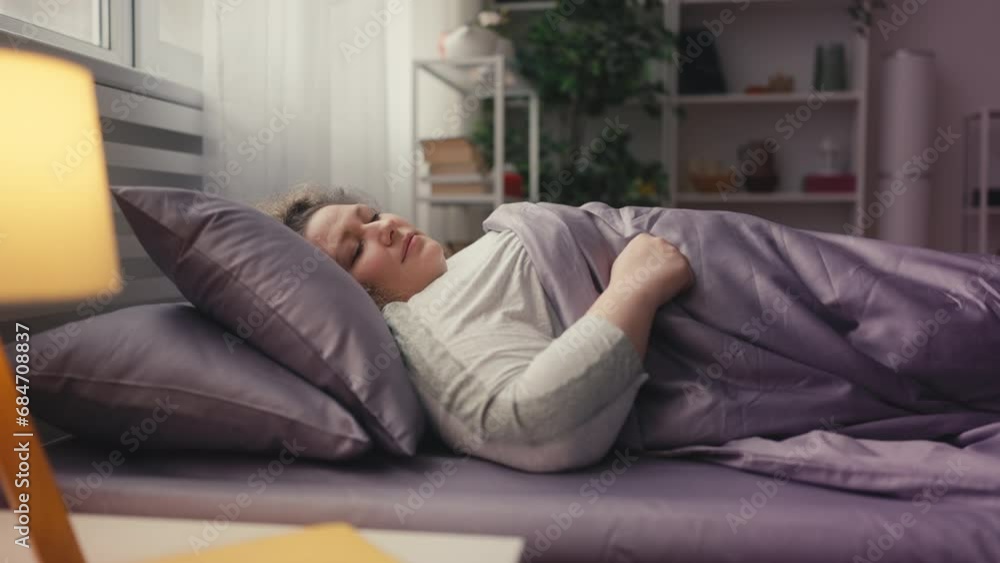 Middle-aged woman sleeping in bed, comfortable rest, orthopedic mattress Middle-aged woman sleeping in bed, comfortable rest, orthopedic mattress