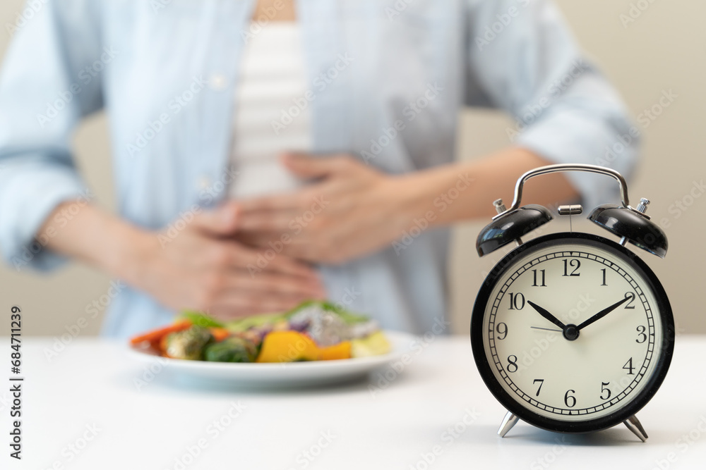 Intermittent fasting concept, Close-up on clock and people feeling hungry waiting time to eat during intermittent fasting diet session - obrazy, fototapety, plakaty 