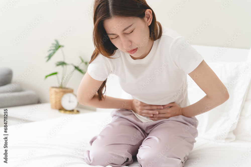 Close-up woman feeling stomach pain from cycle period on the bed at home. Close-up woman feeling stomach pain from cycle period on the bed at home.