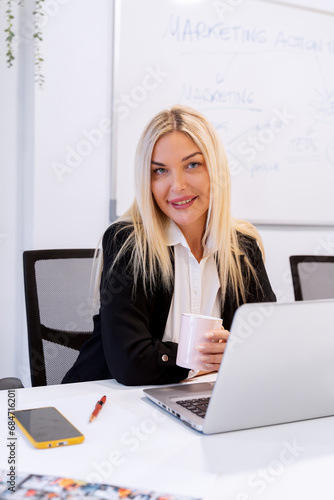 Businesswoman holding a cup of coffee while sitting at her desk in the office. Business concept.