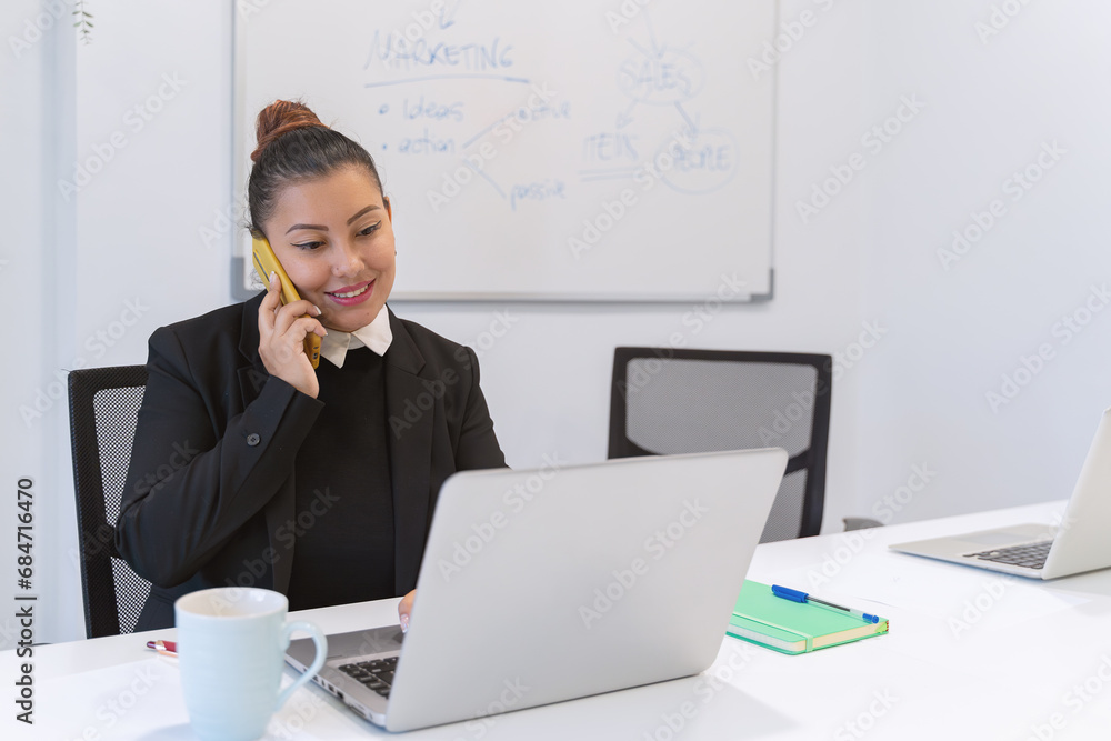 Businesswoman talking on the phone while working with laptop at the office. Business and technology concept. Businesswoman talking on the phone while working with laptop at the office. Business and technology concept.