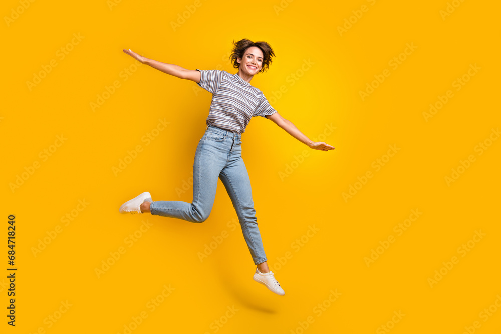 Full length portrait of cheerful pretty person jump arms wings flying empty space isolated on yellow color background