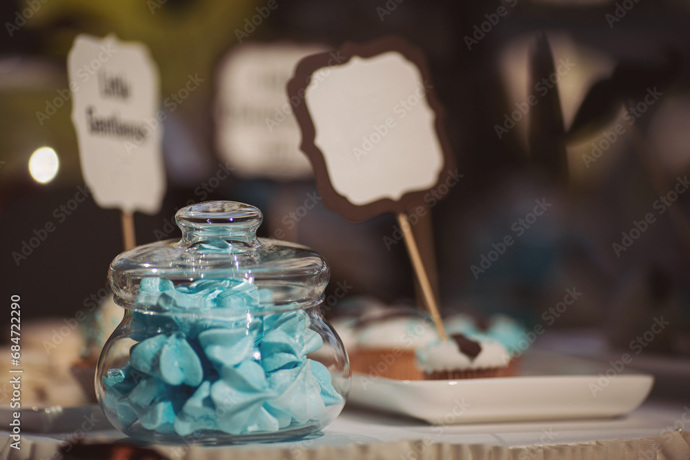 Fototapeta premium Baby shower event, decorations and cakes in blue colour. Sweets and cake on the table ready for party. A beautiful sweet candy bar with muffins, cakes, fruits, marshmallows and toppers.