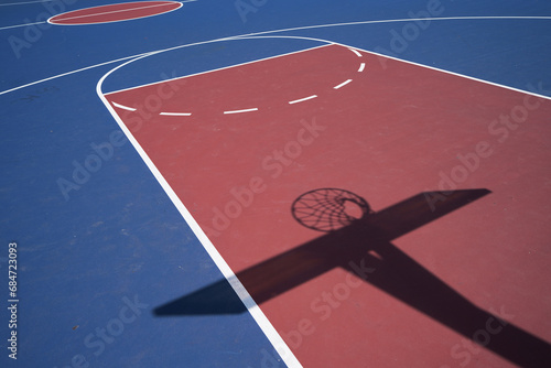 Empty blue outdoor basketball court with the net and backboard in shadow photo