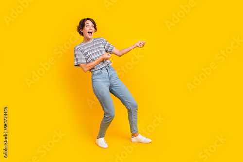 Full body profile portrait of cheerful impressed lady arms pull empty space rope isolated on yellow color background