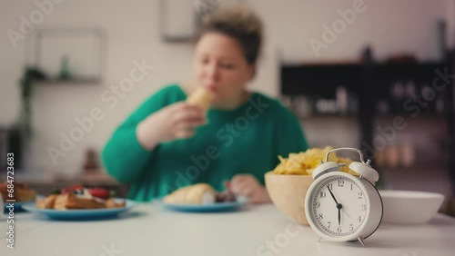Plus size woman overeating sweets and junk food before 6pm, intermittent fasting photo