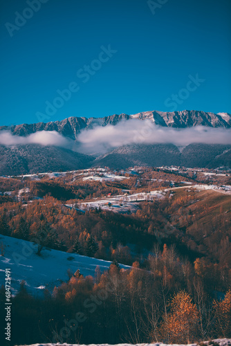 Winter landscape with snow-covered hills and mountains background. Human settlements in wild areas. Villages located in tourist areas