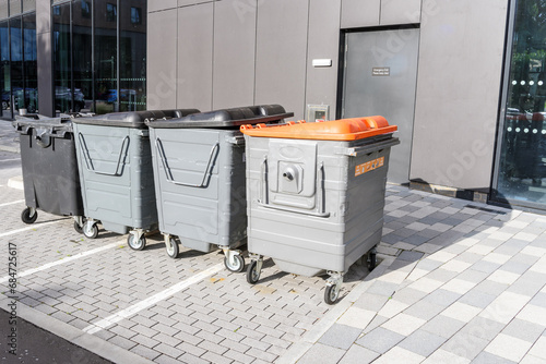 Row of worn out recycing and waste bins in a car park at the back of a modern office building photo