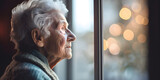 Face of lonely upset senior woman looking through window of nursing house and waiting for family meeting