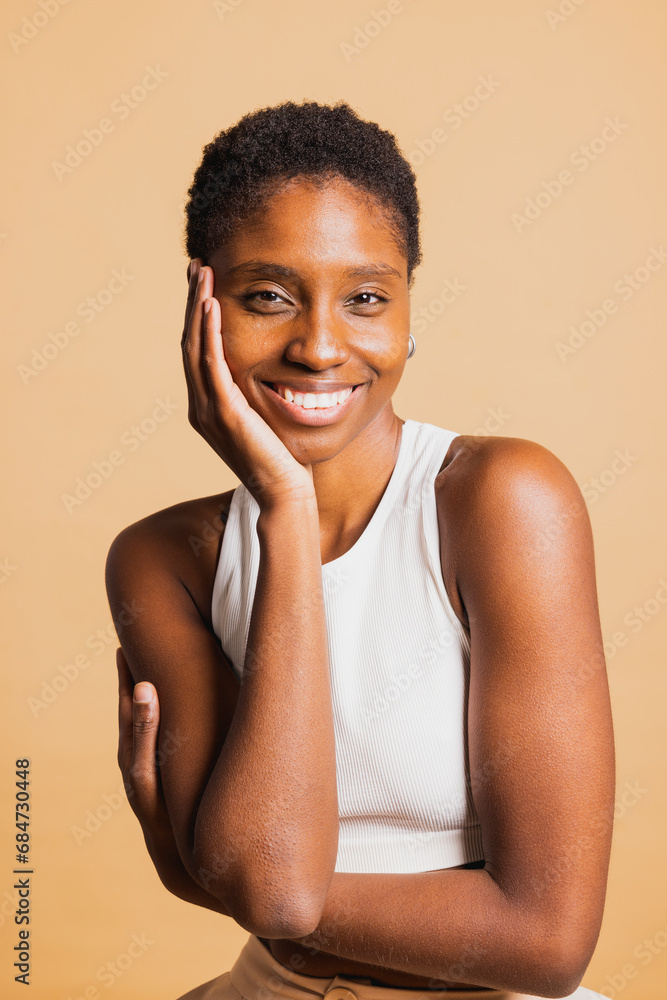 Portrait of a young beautiful african american woman standing against brown background looking at camera with her arms crossed. Young woman standing with her arms crossed. Portrait of a young beautiful african american woman standing against brown background looking at camera with her arms crossed. Young woman standing with her arms crossed.