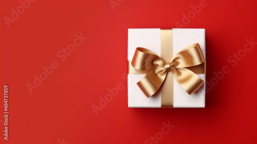 Golden bow and ribbon on white box on red background as Christmas gift concept © Robert Kneschke