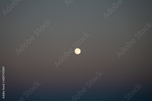Full moon against a subtitle sunset sky.