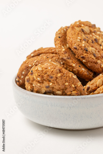 Whole grain cookies with seeds in bowl isolated on white background.  Biscuits with sesame  sunflower and flax seeds close up