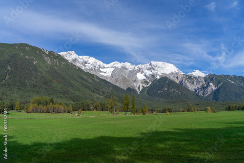 alpine landscape with green meadows and white snowcoverend mountains in the background