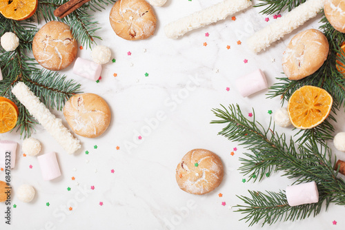 candies and cookies with christmas tree branches on white marble background