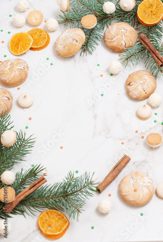 candies and cookies with christmas tree branches on white marble background