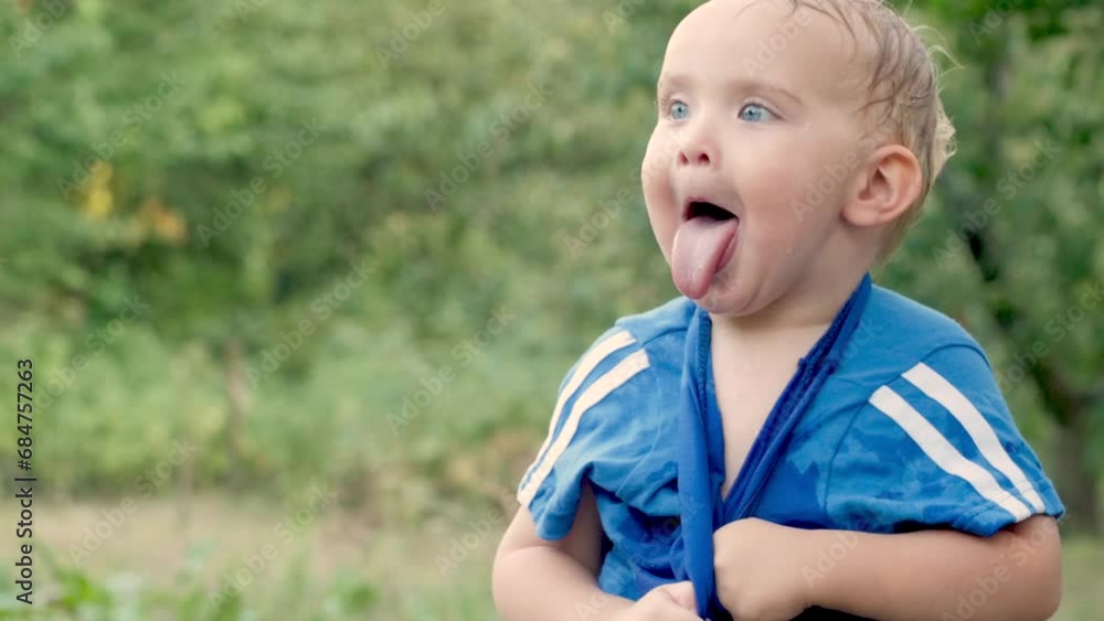 blond little baby boy change wet clothes in summer garden, funny child playing outdoors, happy childhood concept blond little baby boy change wet clothes in summer garden, funny child playing outdoors, happy childhood concept