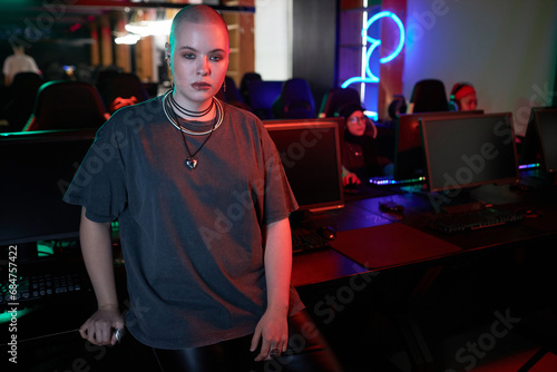 Waist up portrait of gen Z woman posing in gaming club and looking at camera with serious face expression, copy space