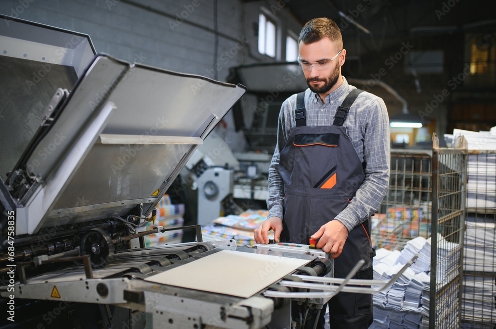 Graphic engineer or worker checking imprint quality in modern print shop Graphic engineer or worker checking imprint quality in modern print shop