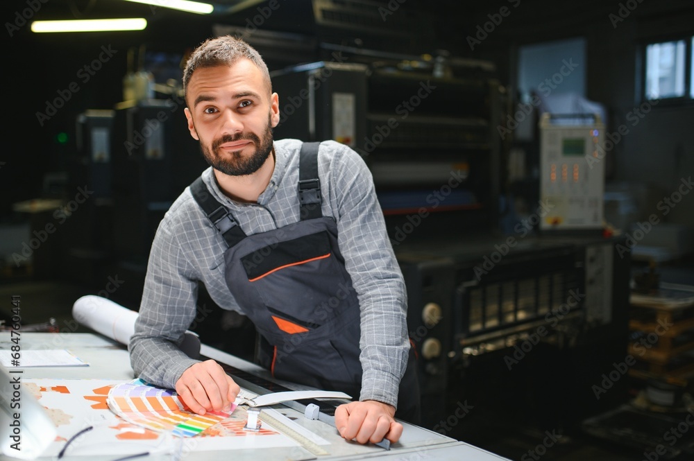Fototapeta premium Graphic engineer or worker checking imprint quality in modern print shop