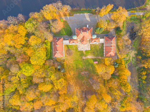 Aaerial view on the beautiful palace in Autumn sunset. White palace in the autumn forest. High altitude.