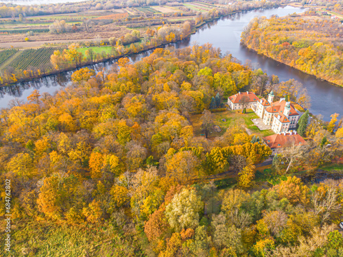 Aaerial view on the beautiful palace in Autumn sunset. White palace in the autumn forest. High altitude.